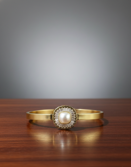 Gold bracelet with a pearl-like center on a wooden surface