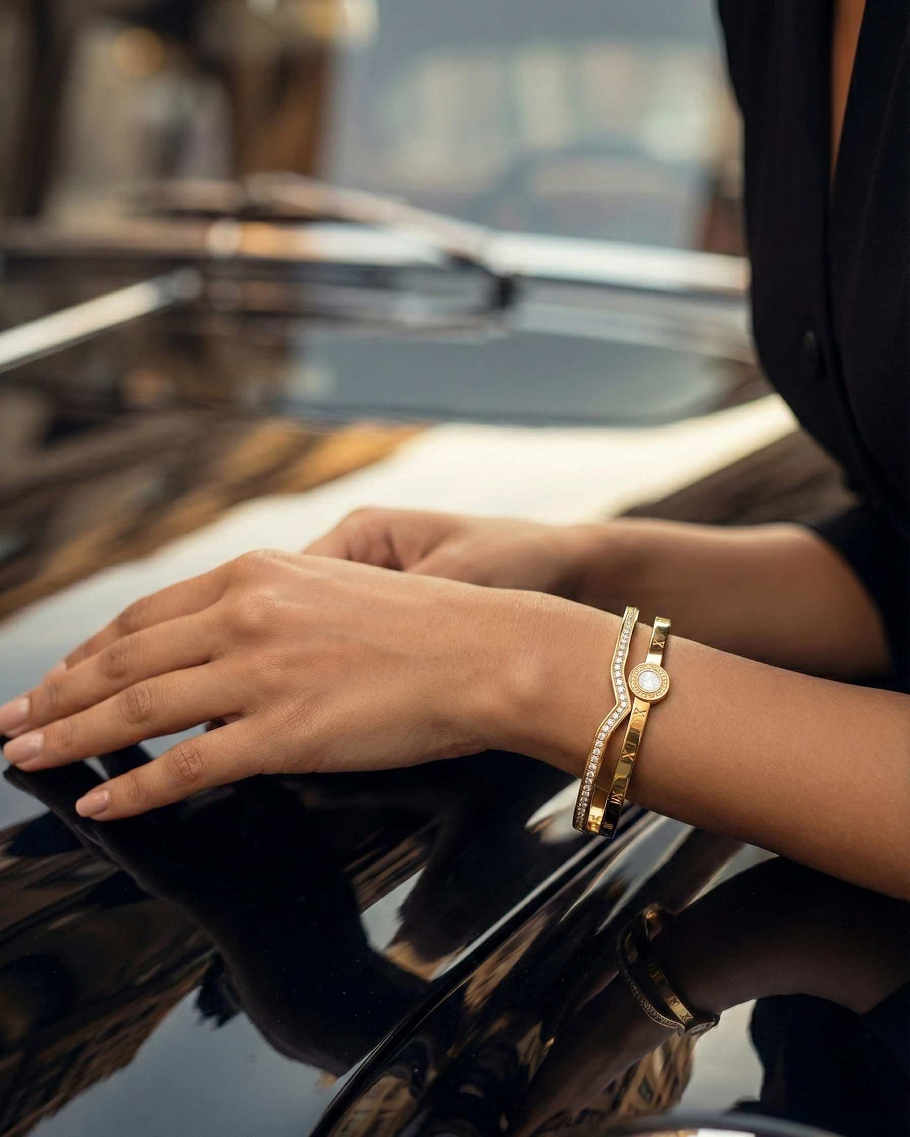 Close-up of hands with a gold watch and bracelet on a reflective surface