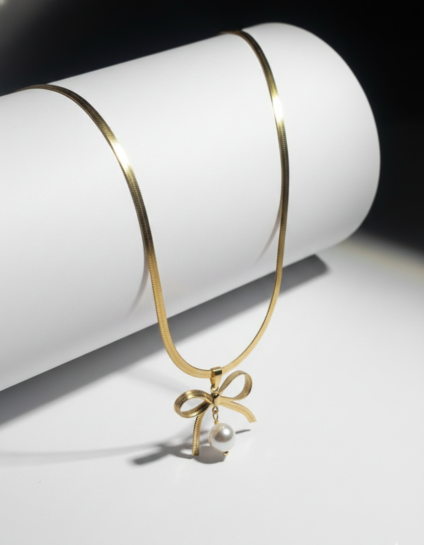 Gold necklace with a bow and pearl pendant on a white background