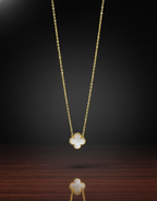 Gold necklace with a clover-shaped pendant on a dark background