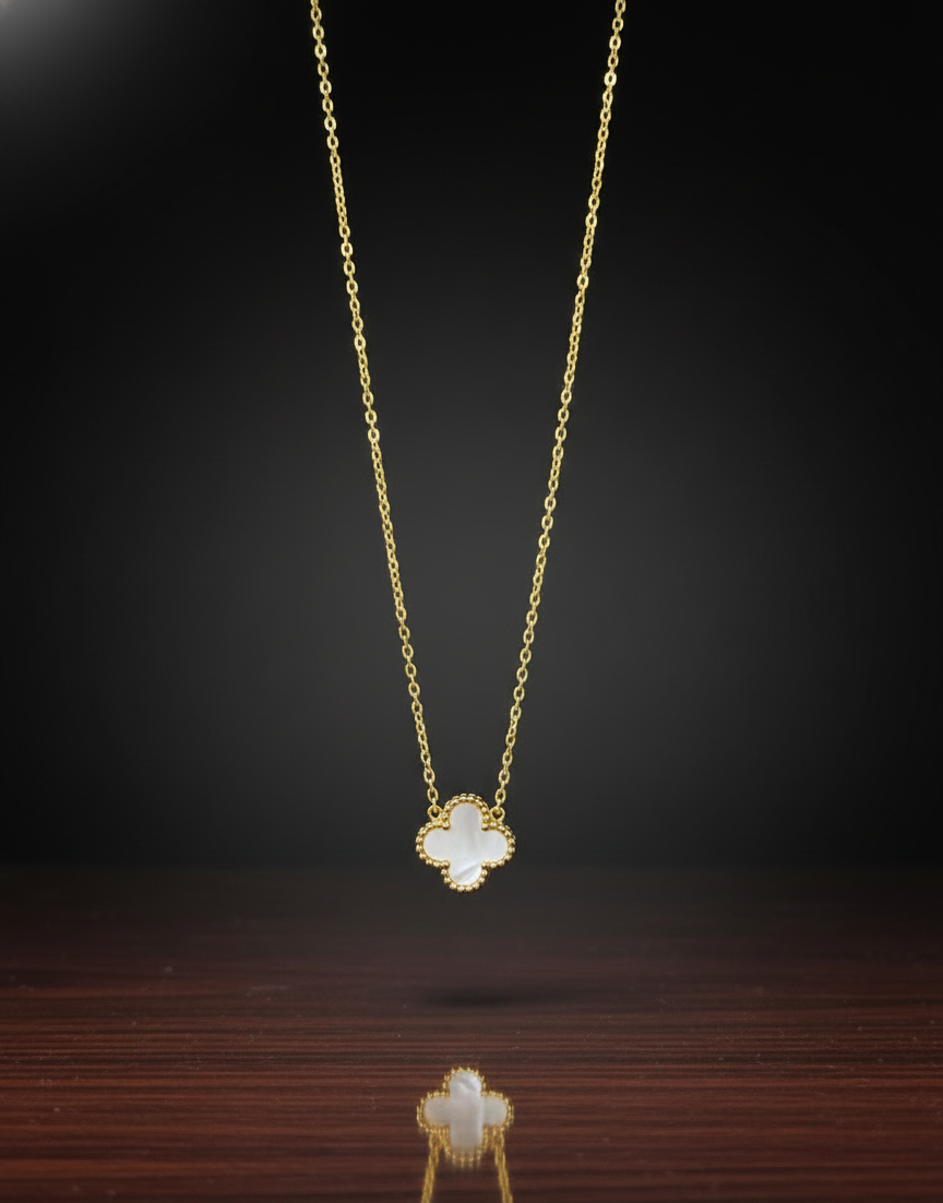 Gold necklace with a clover-shaped pendant on a dark background
