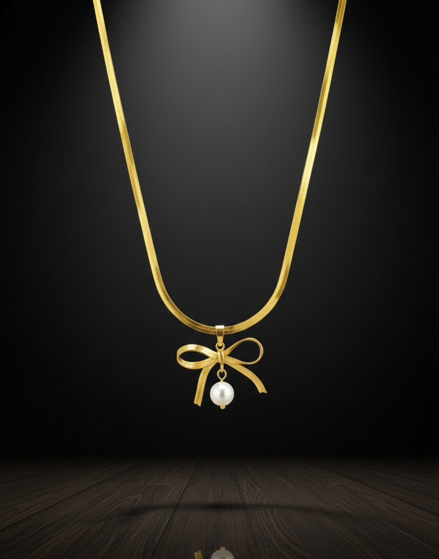 Gold necklace with a bow and pearl pendant on a dark background