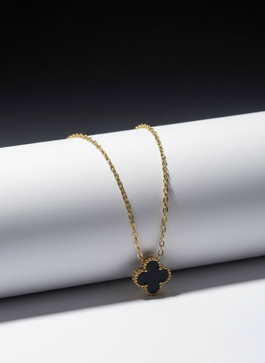 Gold necklace with a black pendant on a white surface