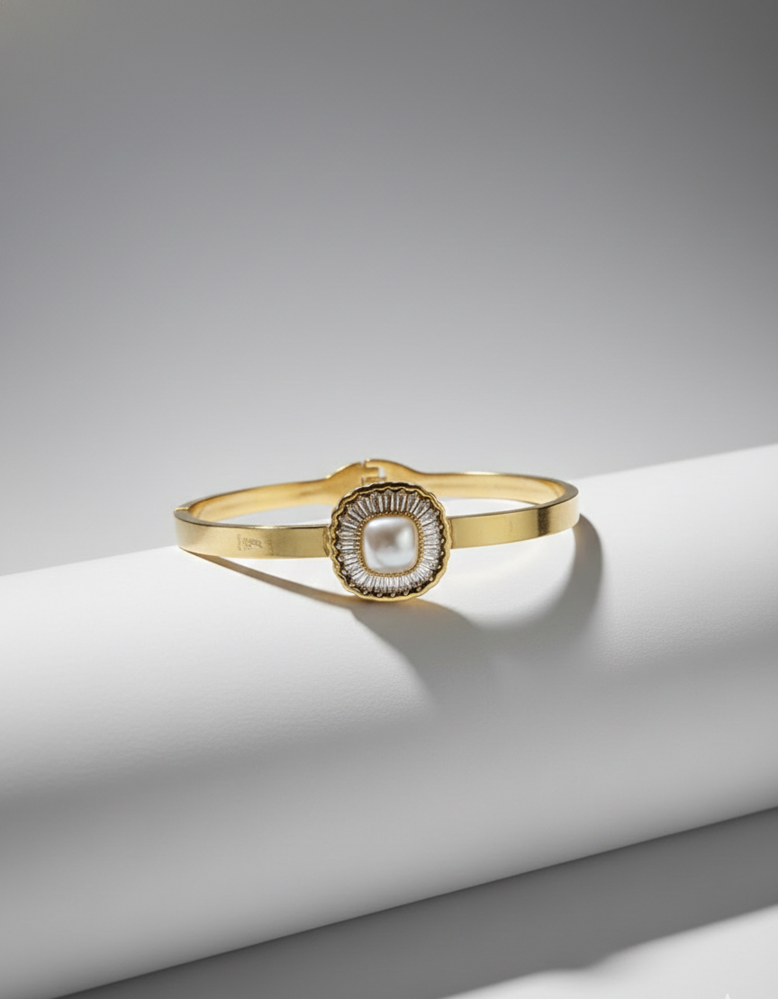 Gold bracelet with a central pearl on a white surface