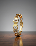 Gold bracelet with diamond accents on a wooden surface and gray background