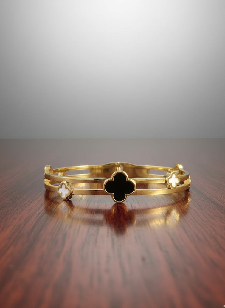Gold bracelet with clover design on a wooden surface