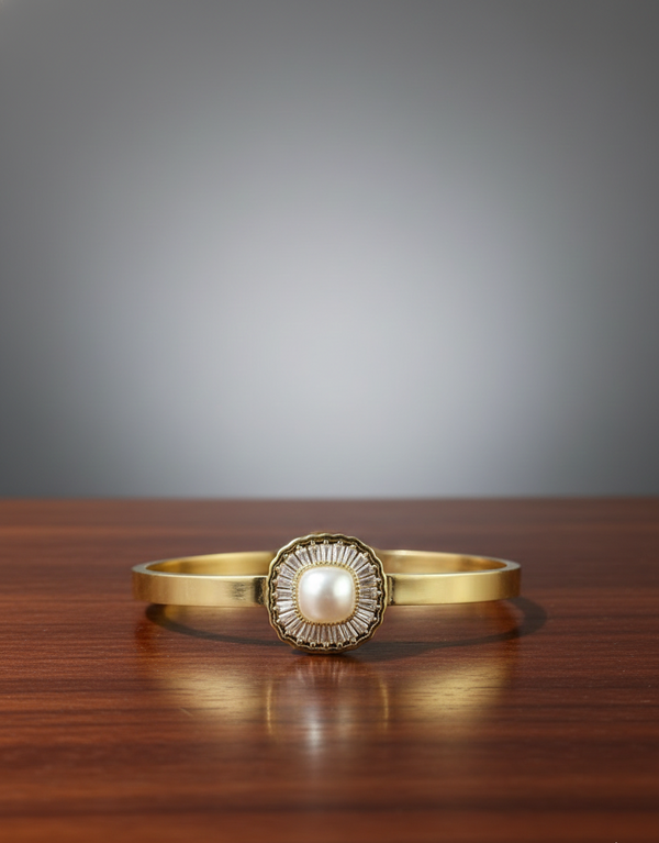 Gold bracelet with a pearl-like center on a wooden surface
