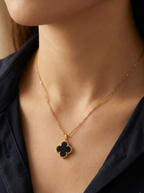 Gold necklace with a clover-shaped pendant worn by a person