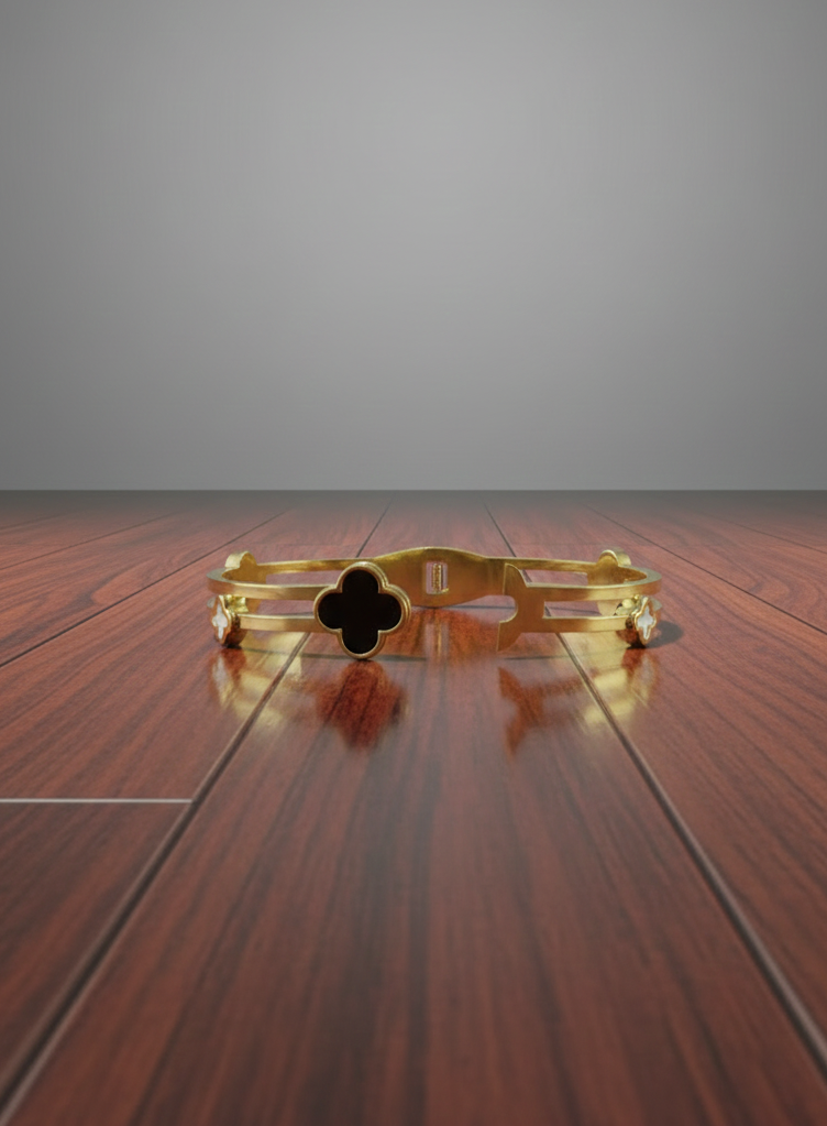 Gold bracelet with a clover design on a wooden surface with a gray background