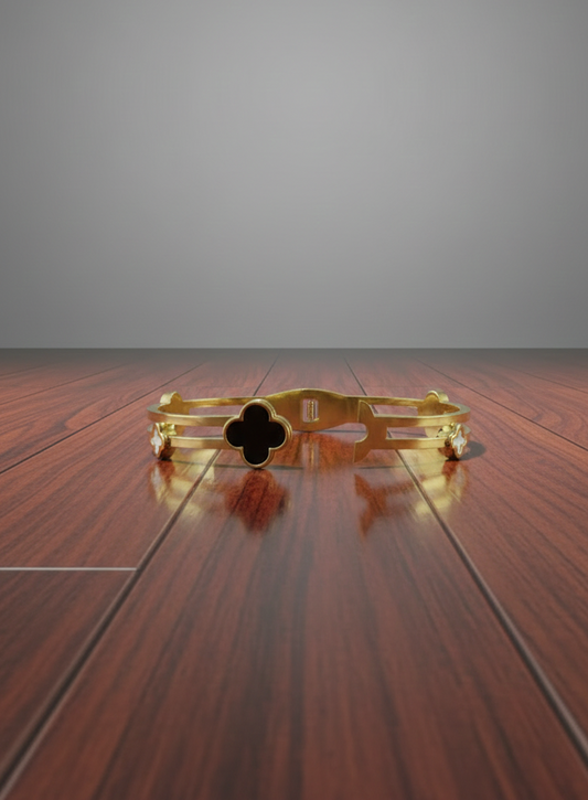 Gold bracelet with a clover design on a wooden surface with a gray background