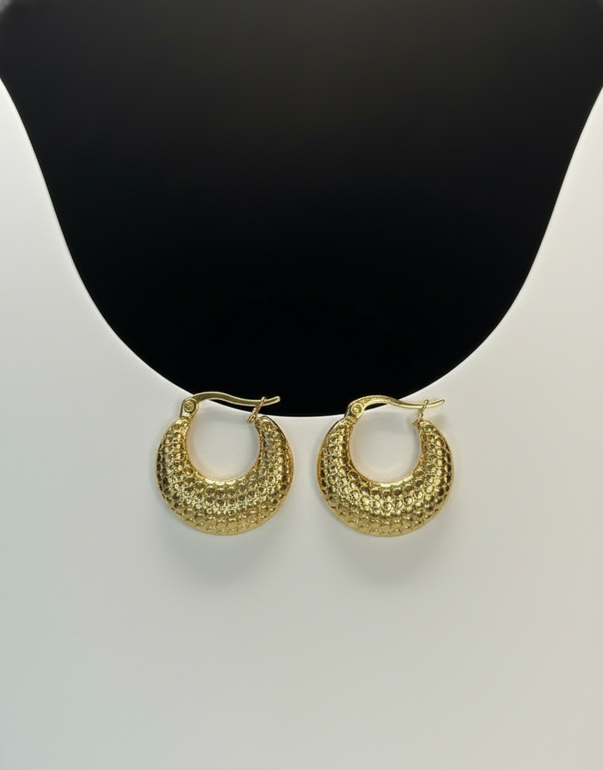 Gold hoop earrings on a mannequin bust with a plain background